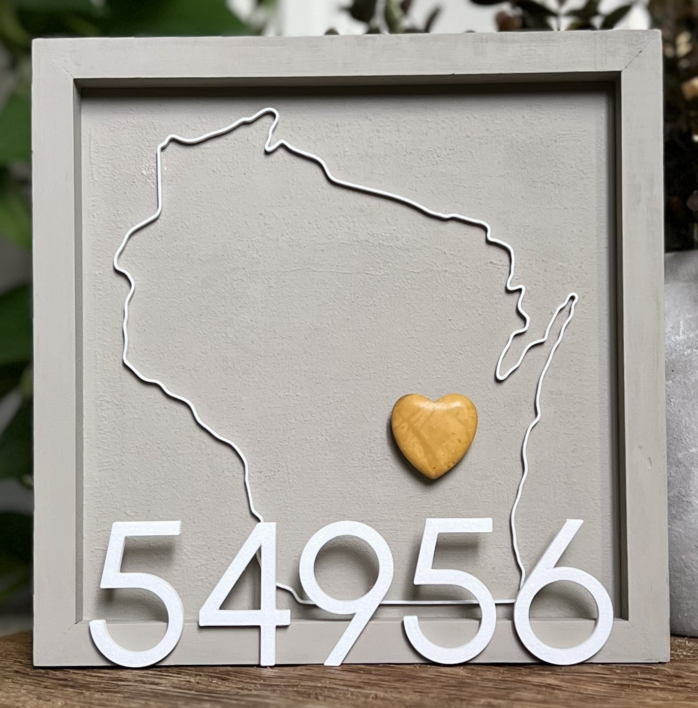 Square framed magnet board with a 3D-printed Wisconsin outline and movable heart magnet.